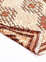 Alfombra oriental de lana con diseño geométrico y motivos florales. Colores cálidos y textura densa.